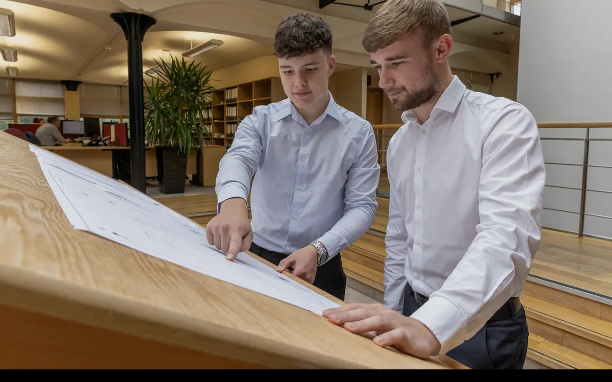 Two people reviewing a printed document at an office desk