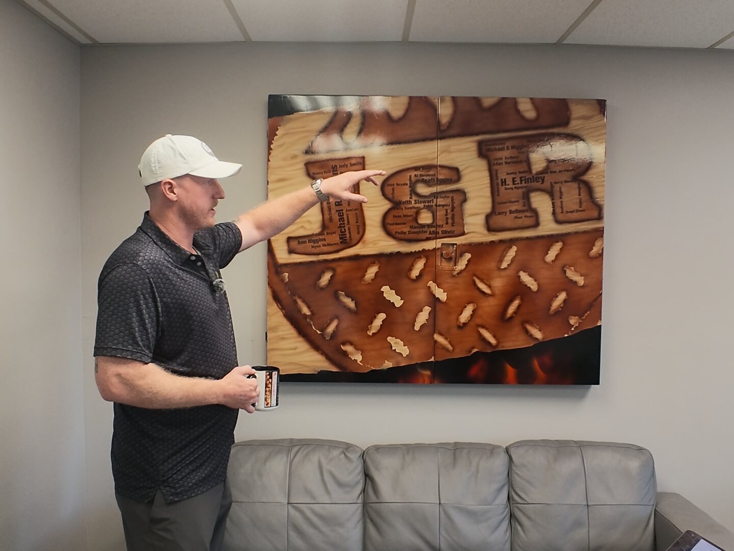 Ryan Higgins pointing at the J&R logo painting in the shop's front office